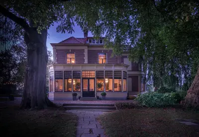 a large house with its lights on at night at Logement aan de Vecht in Breukelen