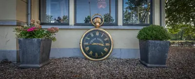a clock is sitting in front of a building at Logement aan de Vecht in Breukelen