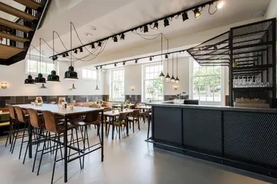 a dining room with tables and chairs and windows at Boutique Hotel d'Oude Morsch in Leiden