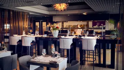 a restaurant with a bar with white tables and chairs at WestCord Fashion Hotel Amsterdam in Amsterdam