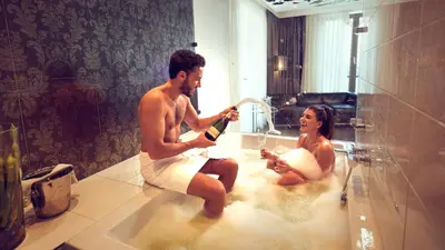 a man and a woman sitting in a bathtub playing at WestCord Fashion Hotel Amsterdam in Amsterdam