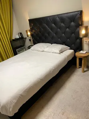 a bedroom with a large bed with a black headboard at Camp-Inn Hotel in Amsterdam