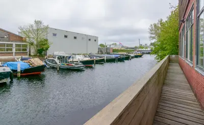 a group of boats docked in a river next to a building at Camp-Inn Hotel in Amsterdam