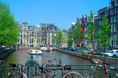 a group of bikes parked next to a river with buildings at Camp-Inn Hotel in Amsterdam