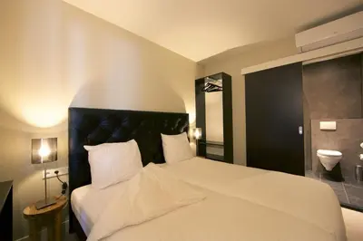a bedroom with a white bed with a black headboard at Camp-Inn Hotel in Amsterdam