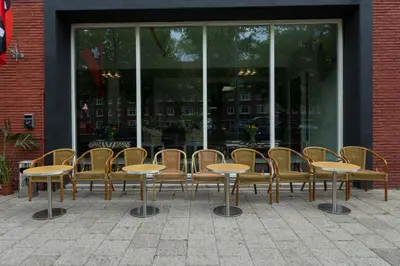a group of tables and chairs in front of a building at Camp-Inn Hotel in Amsterdam
