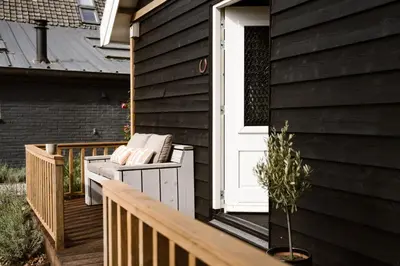 a wooden porch with a white door and a house at Ruyge Weyde Logies, Eco Farm in Oudewater