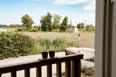 a balcony with two black cups on a fence at Ruyge Weyde Logies, Eco Farm in Oudewater