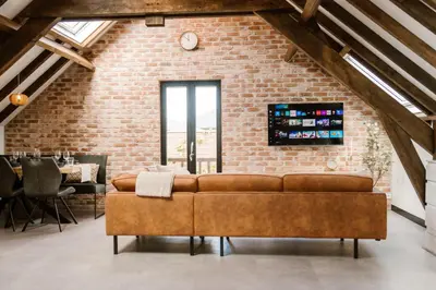a living room with a brown couch in front of a brick wall at Ruyge Weyde Logies, Eco Farm in Oudewater