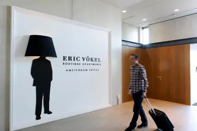 a man pulling a suitcase in front of a wall with a silhouette at Eric Vökel Boutique Apartments - Amsterdam Suites in Amsterdam