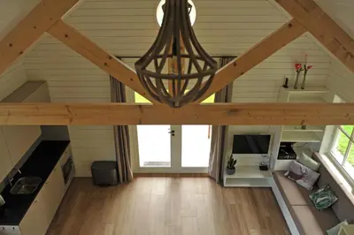 an attic room with a wooden ceiling and a chandelier at Lodges near the Rhine - Sustainable Residence in Hazerswoude-Rijndijk