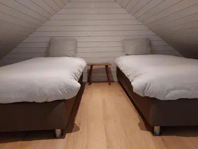 two beds in a room with a table between them at Lodges near the Rhine - Sustainable Residence in Hazerswoude-Rijndijk