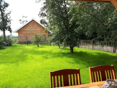 two wooden benches sitting in a yard with a fence at Lodges near the Rhine - Sustainable Residence in Hazerswoude-Rijndijk