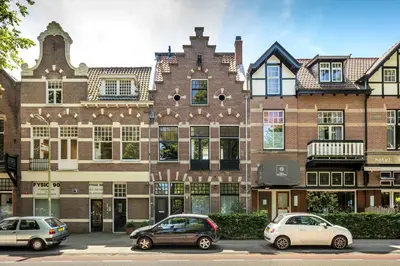 two cars parked in front of a large brick building at Bloemendaal Hotel Collection Apartments in Bloemendaal