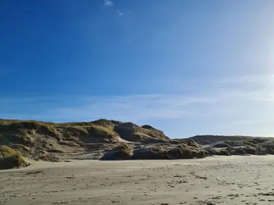 a sandy beach with rocks and a blue sky at Bloemendaal Hotel Collection Apartments in Bloemendaal