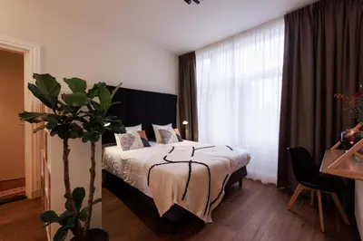 a bedroom with a bed and a large window at Bloemendaal Hotel Collection Apartments in Bloemendaal