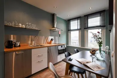 a kitchen with a table and a dining room at Bloemendaal Hotel Collection Apartments in Bloemendaal
