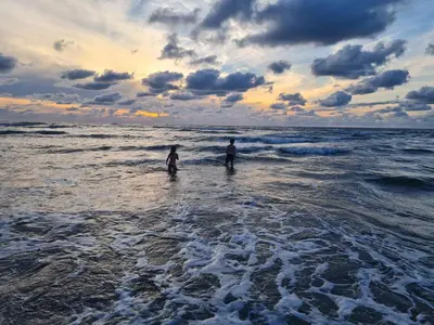 two people standing in the water at the beach at Bloemendaal Hotel Collection Apartments in Bloemendaal