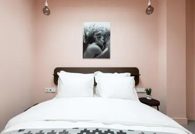 a bedroom with a white bed with a picture on the wall at Kith & Kin Boutique Apartments in Amsterdam