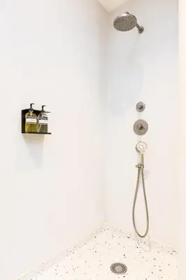 a shower in a white bathroom with a shower head at Kith & Kin Boutique Apartments in Amsterdam