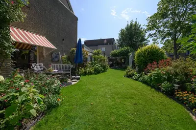 a garden with some flowers and a building at Bed and Breakfast Ineke en John in Hoofddorp