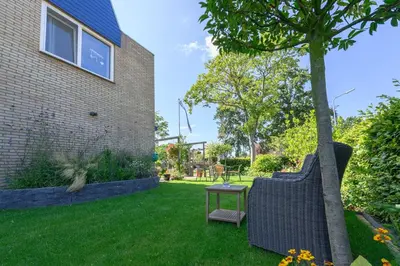 a yard with two chairs and a table next to a tree at Bed and Breakfast Ineke en John in Hoofddorp