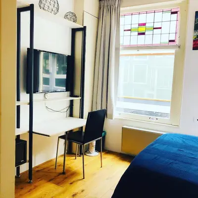 a bedroom with a desk and a bed and a window at Mercedes Bed&Breakfast Amsterdam in Amsterdam