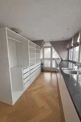 a kitchen with white cabinets and a wooden floor at Residance Anne's Beach in Zandvoort