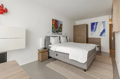 a white bedroom with a bed and a tv at Black Jack Suites in Amsterdam
