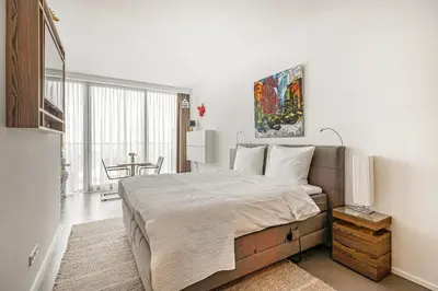 a white bedroom with a large bed and a table at Black Jack Suites in Amsterdam