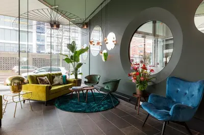 a living room with a yellow couch and blue chairs at Hotel2Stay in Amsterdam