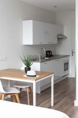a white kitchen with a wooden table and chairs at Hotel2Stay in Amsterdam