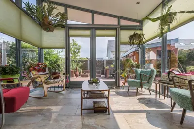 an indoor patio with chairs and tables and windows at Casa Mirador Sleep Inn in Almere