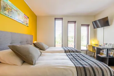a bedroom with two beds with yellow walls and windows at Casa Mirador Sleep Inn in Almere