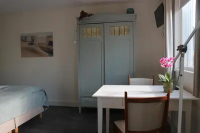 a bedroom with a bed and a table and a cabinet at B&B - Pension Het Oude Dorp in Katwijk