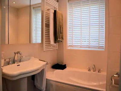 a white bathroom with a sink and a tub at Holiday Home in Noordwijk near Beach in Noordwijk