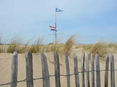 a wooden fence in front of a sandy beach at Holiday Home in Noordwijk near Beach in Noordwijk