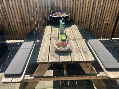a wooden picnic table with a bowl of plants on it at Ferienhaus Glücklich am Meer 1 mit Wellnesszugang in Egmond aan Zee