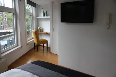 a bedroom with a bed and a television on a wall at Bridge Inn in Amsterdam