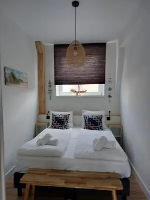 a bedroom with a white bed with a window at Benny's Beach House 2 in Zandvoort
