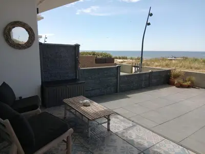a patio with a chair and a table and the ocean at Benny's Beach House 2 in Zandvoort