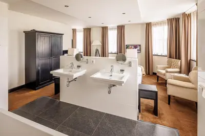 a bathroom with two sinks and a living room at Grand Hotel Alkmaar in Alkmaar