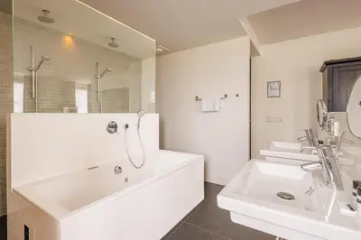a white bathroom with a tub and a sink at Grand Hotel Alkmaar in Alkmaar