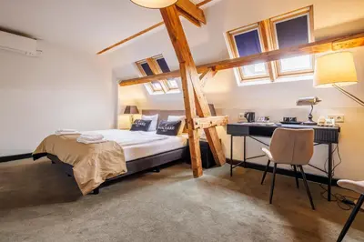 a bedroom with a bed and a desk and windows at Grand Hotel Alkmaar in Alkmaar