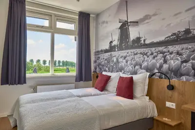 a bedroom with a bed and a large window at Hotel VILLA GROET in Avenhorn