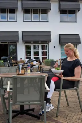 a woman sitting at a table with a bowl of food at Hotel VILLA GROET in Avenhorn