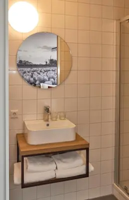 a bathroom with a sink and a mirror at Hotel VILLA GROET in Avenhorn