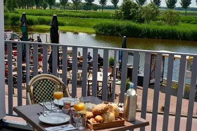 a table with a basket of bread and juice on a balcony at Hotel VILLA GROET in Avenhorn