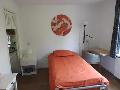 a bedroom with a bed with an orange sheet on the wall at MY-A-Mi-Go-S in Muiderberg