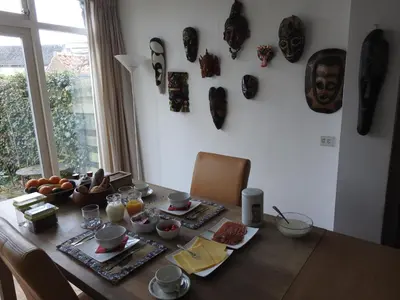 a dining room table with masks on the wall at MY-A-Mi-Go-S in Muiderberg